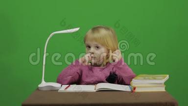 女孩坐在桌子旁，<strong>抠</strong>鼻子！ 课堂中的教育过程.. 快乐的三岁女孩